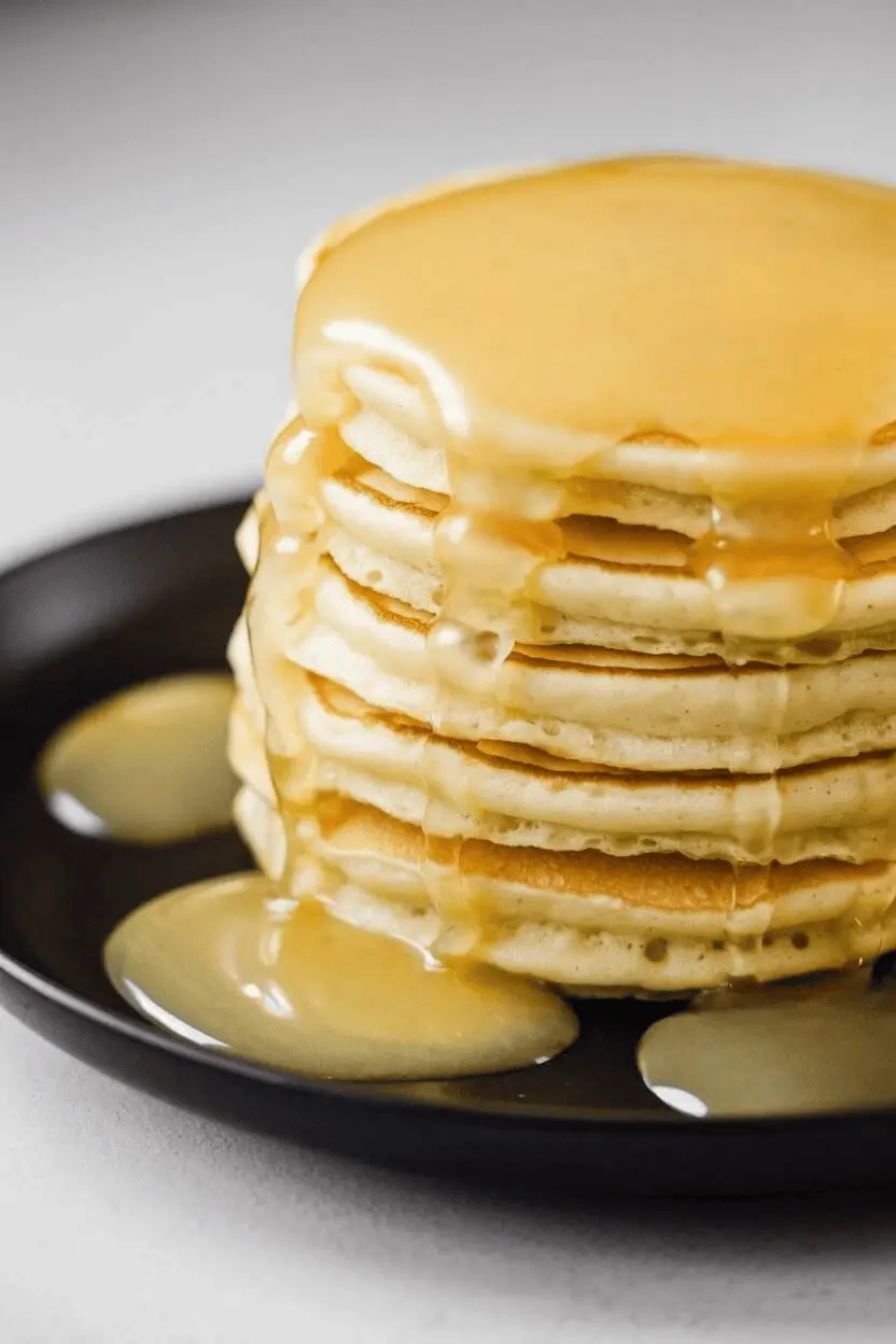 Close-up image of pancakes on a black plate topped with lemon compote.