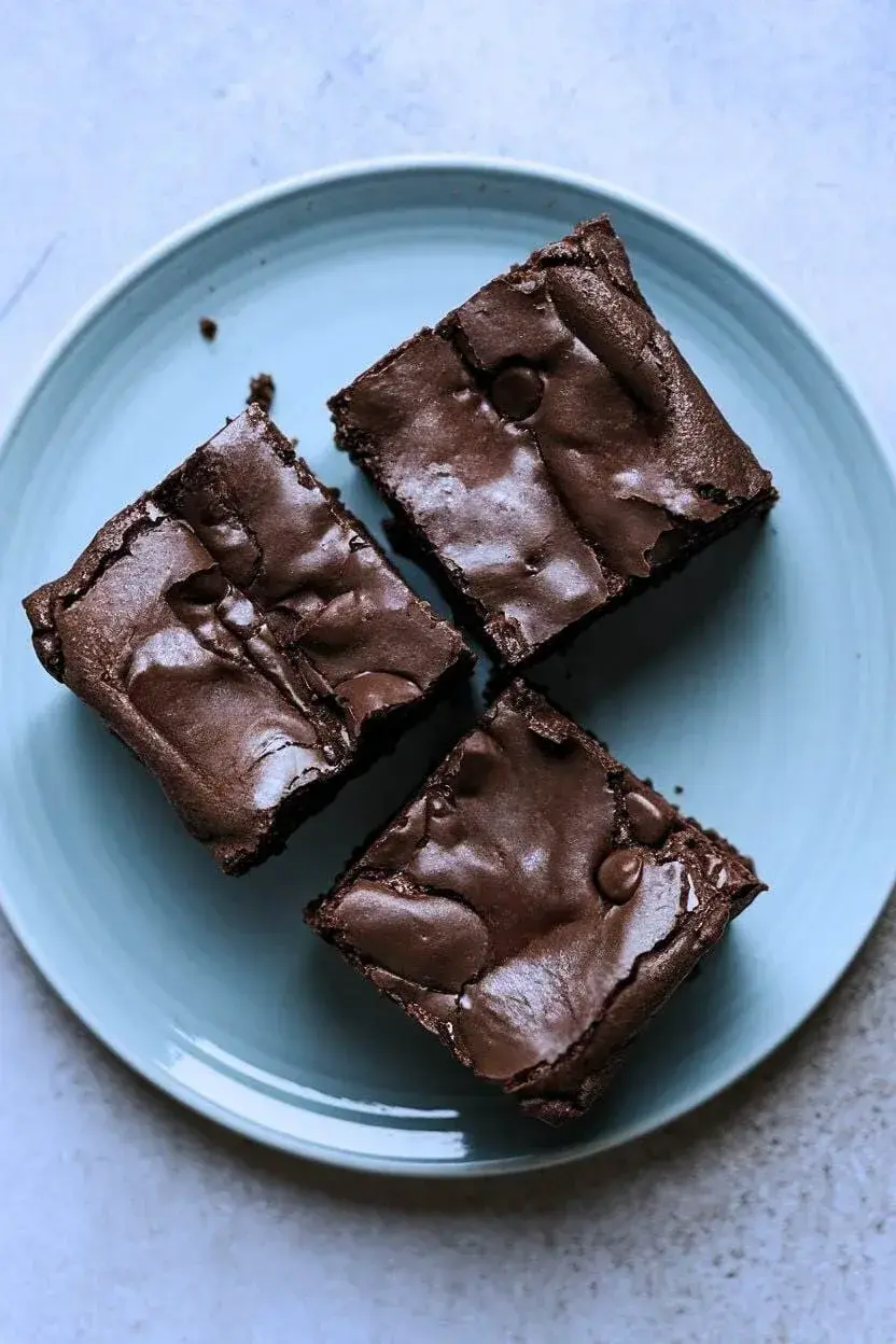 top-down view of three banana brownies on a light blue plate atop a light gray background.